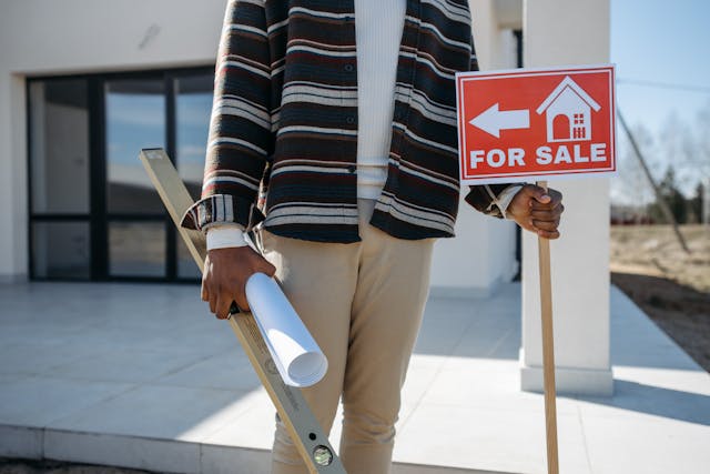 person-holding-for-sale-sign-outside-of-home