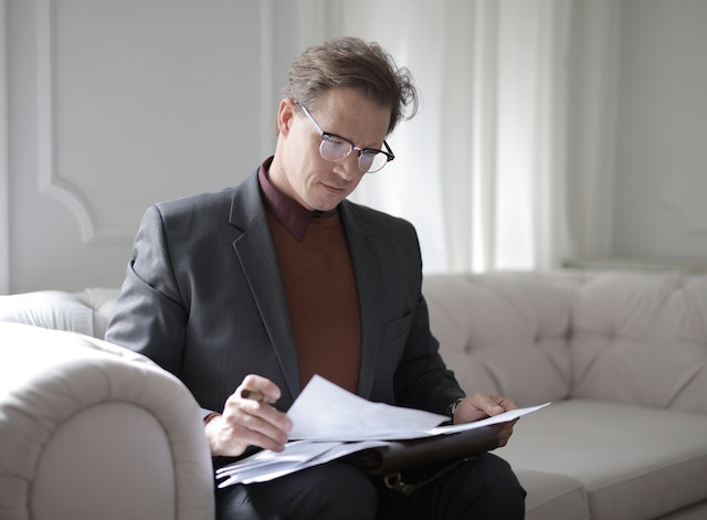 A property owner sitting on a white couch reviewing a lease